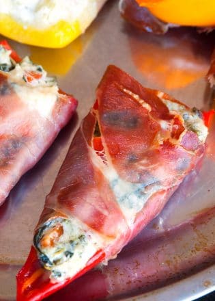 Spinach artichoke stuffed peppers wrapped in prosciutto. Add this to your appetizer recipes. Spinach dip, bell peppers, prosciutto - it sounds like heaven. It has a little kick from jalapenos too. The perfect party food recipe. | thebewitchinkitchen.com