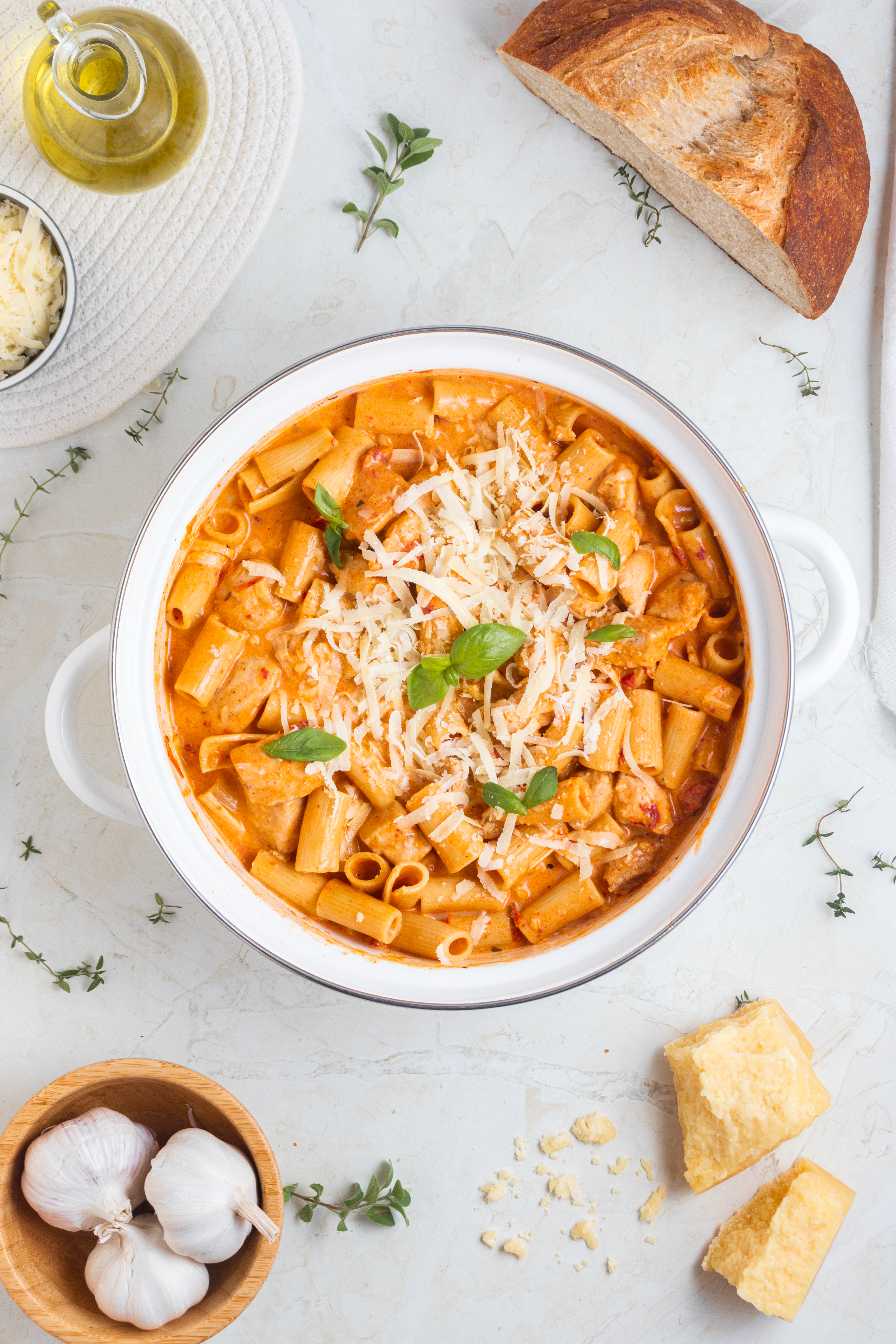 Marry Me Chicken pasta next to garlic, bread, and rosemary spices