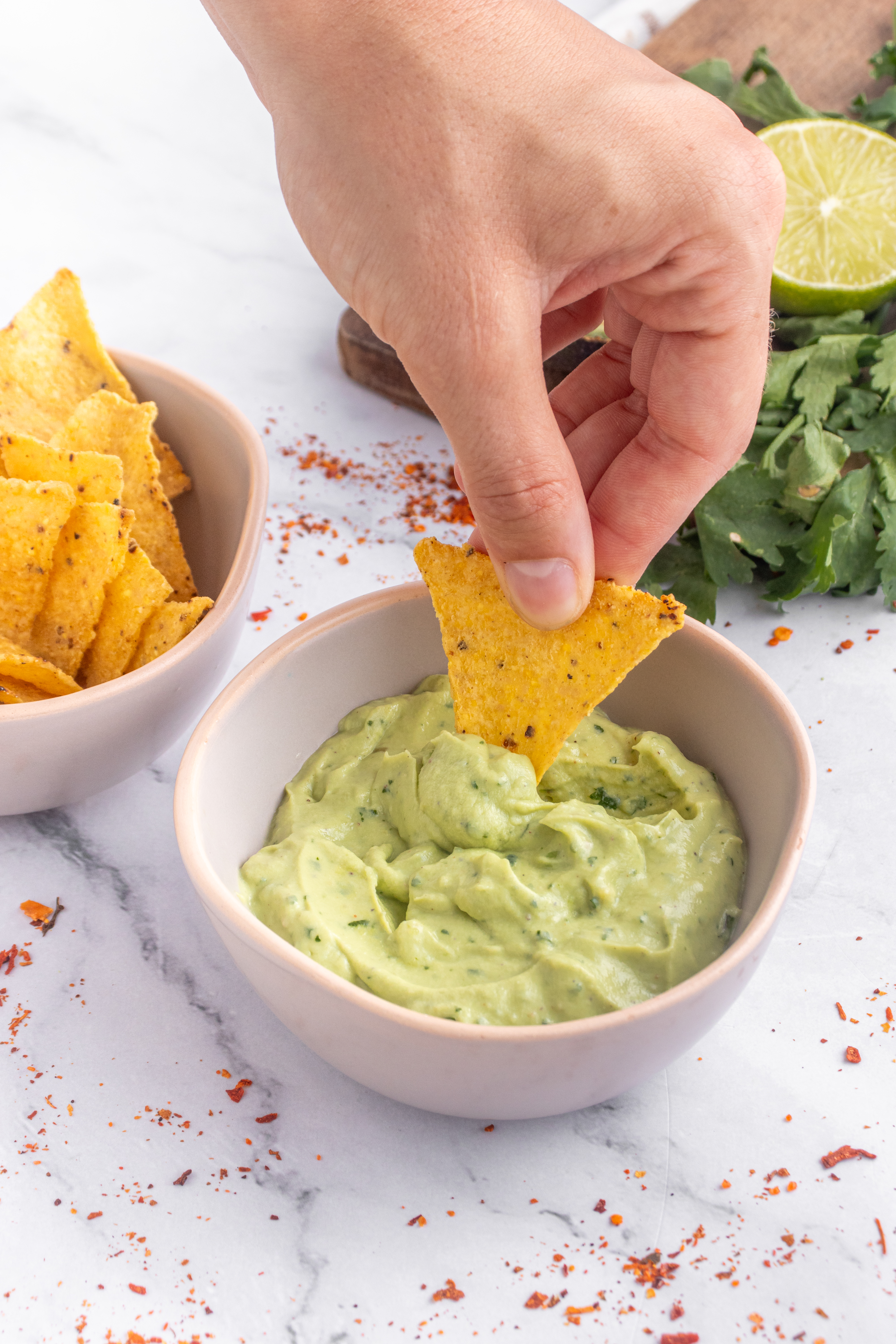 dipping a tortilla chip into avocado crema