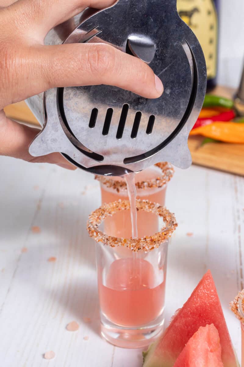 pouring Mexican candy shots from a shaker to a shot glass