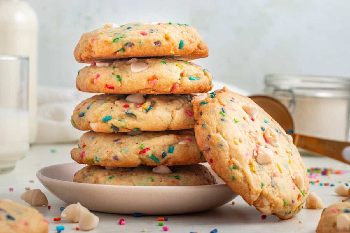 Five cookies stacked on a plate with one leaning against them