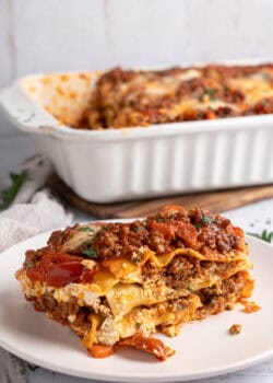 Lasagna served with a baking dish behind it