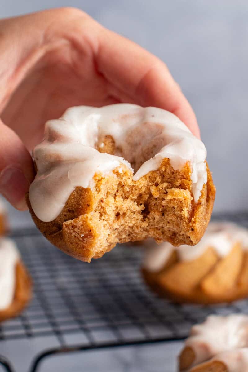 Hand holding a glazed pumpkin bundt cake that has a bite take out of it