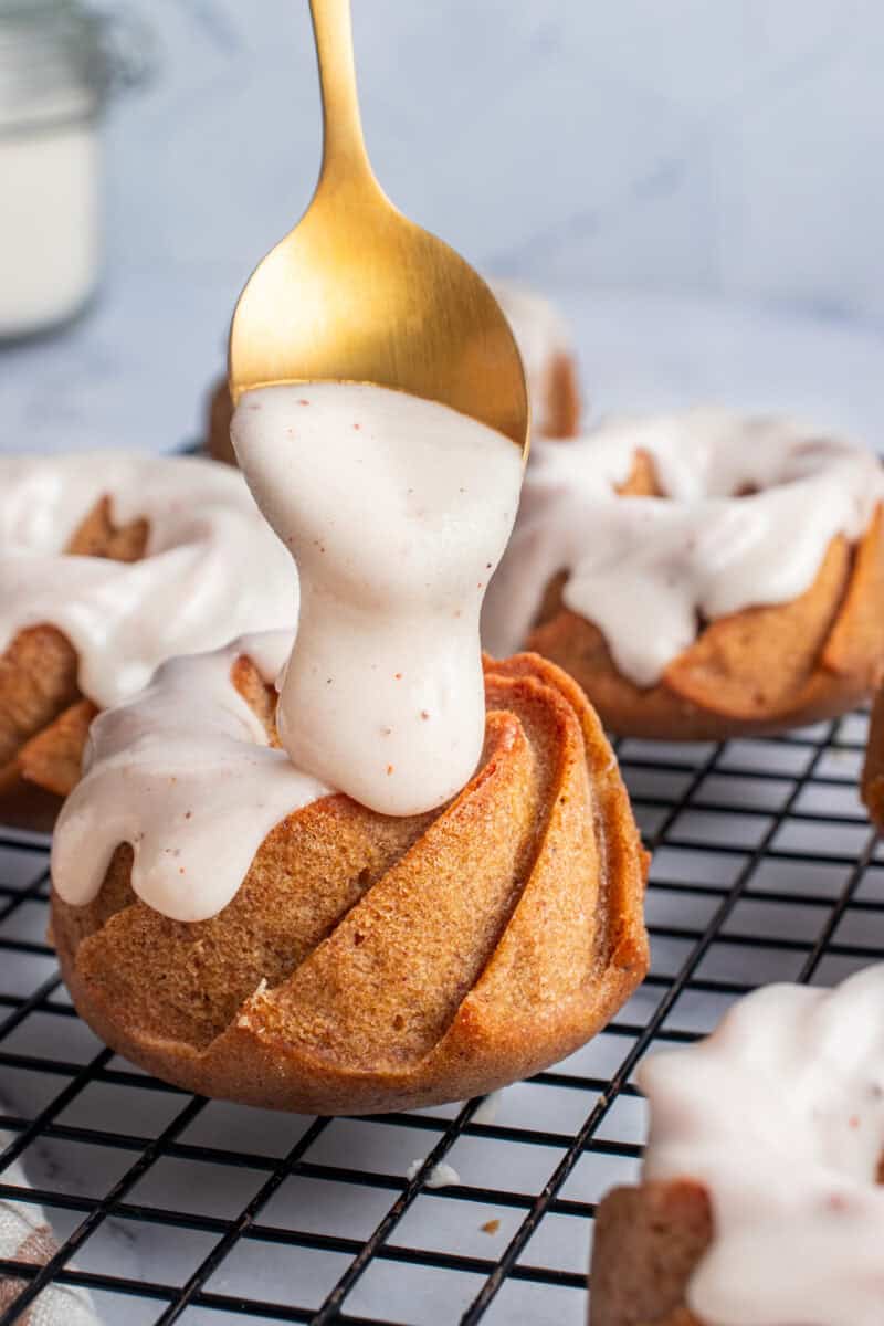 Glaze being poured over a pumpkin mini bundt cake